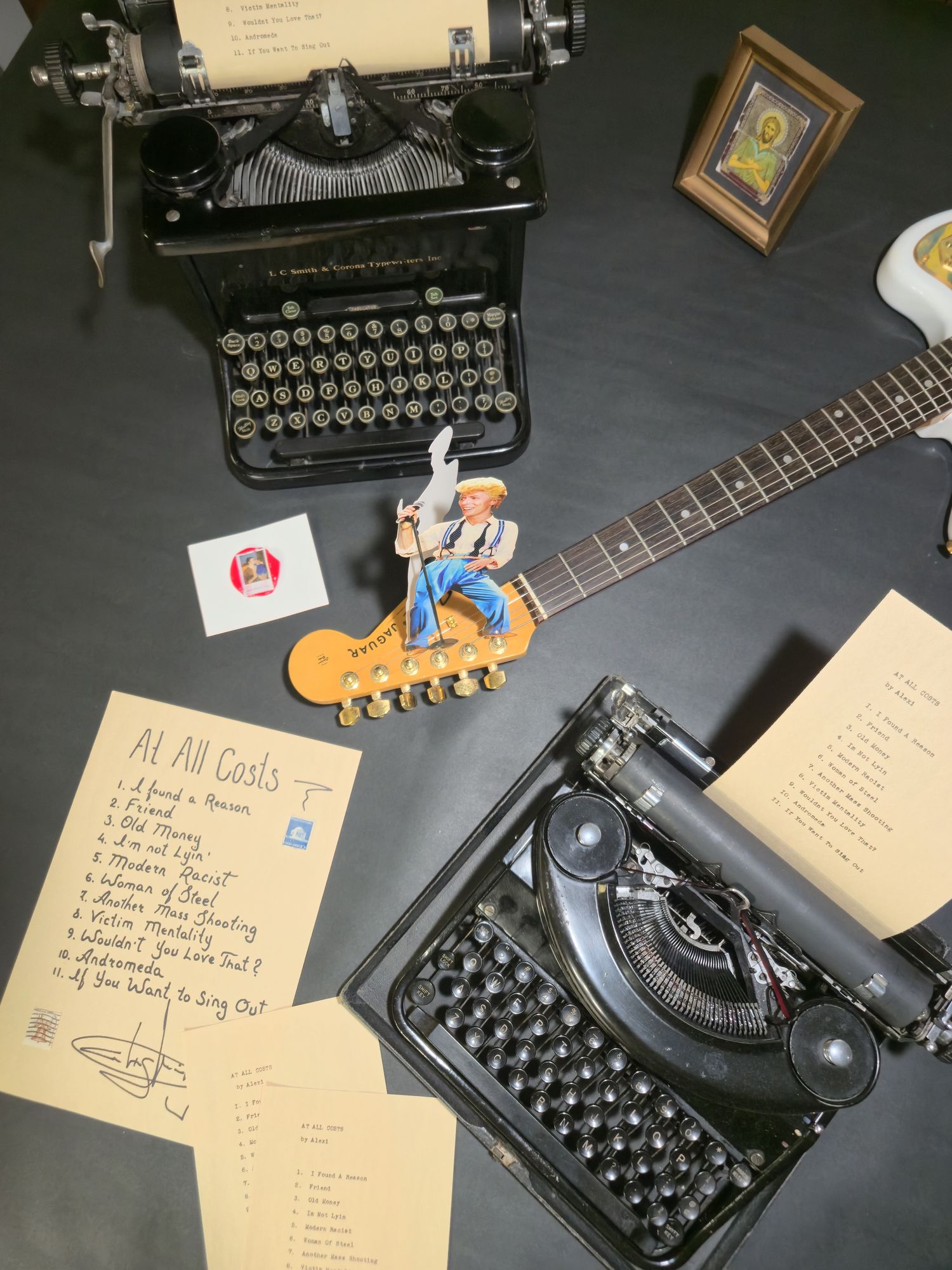Typewriter, manuscript pages and a guitar on the studio table